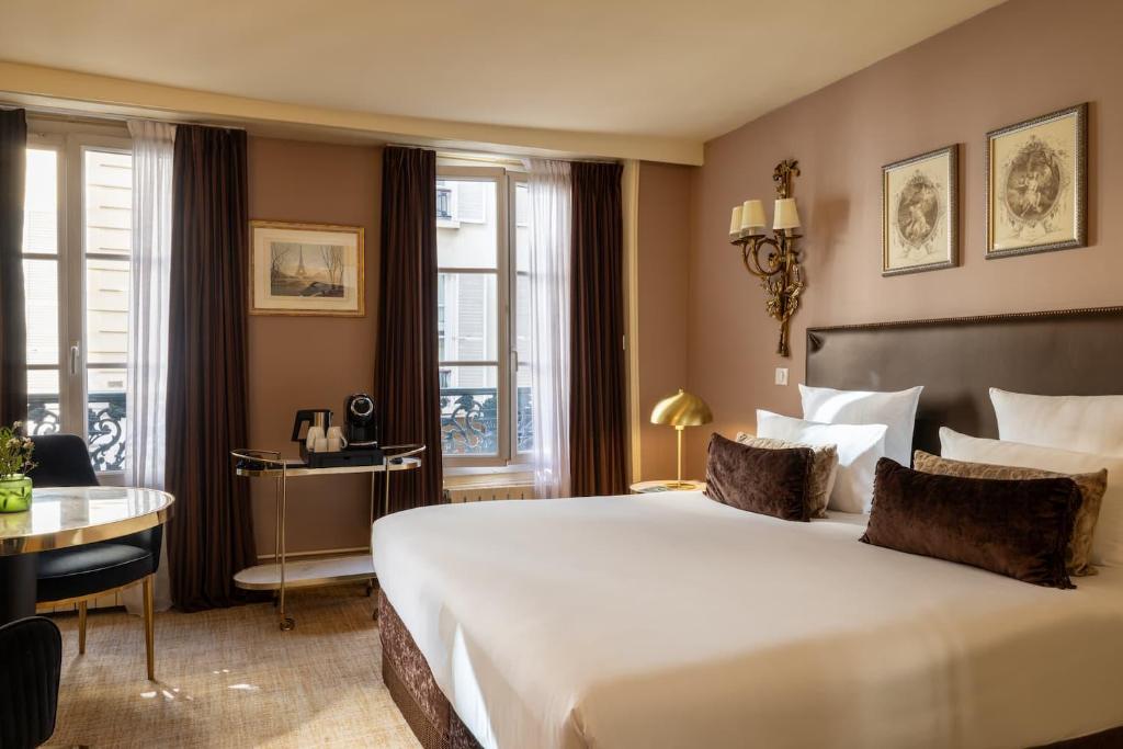 Una habitación de hotel con una cama grande y un escritorio. en Hotel Des Deux Continents, en París