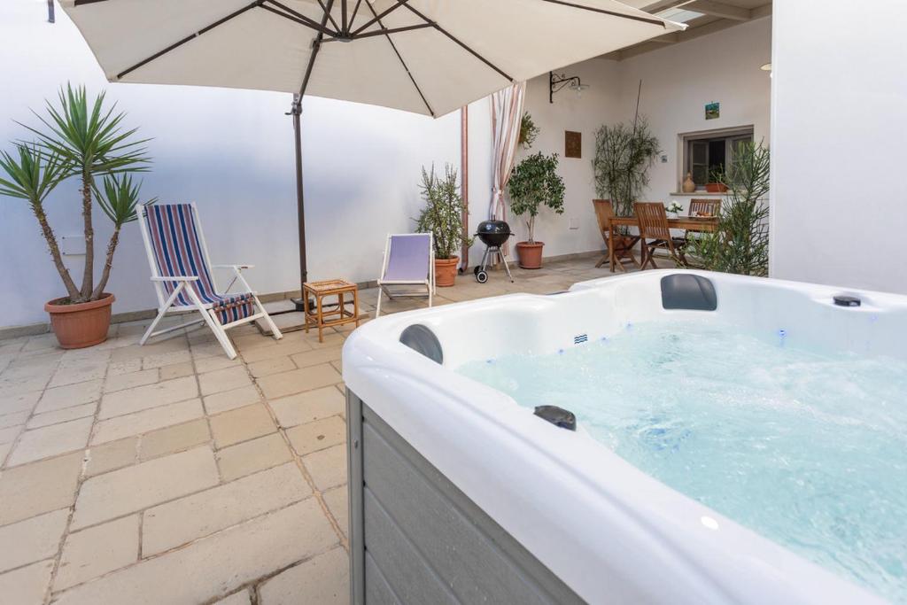 a hot tub with an umbrella in a patio at Giardino dellorologio - Salento Reservation in Racale
