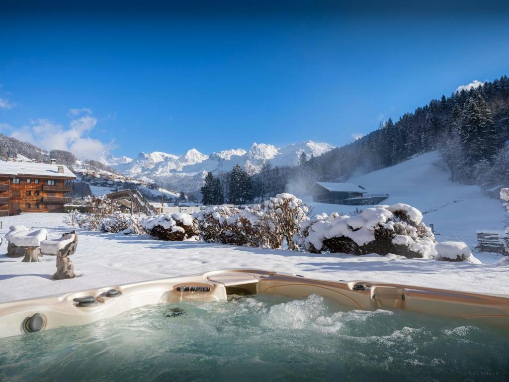 einen Whirlpool im Schnee mit schneebedeckten Bergen in der Unterkunft Chalet Ibusta - OVO Network in Le Grand-Bornand