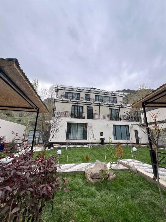 Zamin Dacha的一座白色的大建筑,前面有一个院子