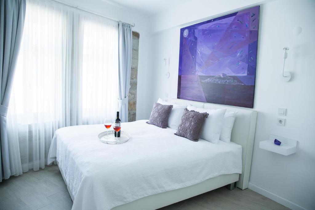Dormitorio blanco con cama blanca y mesa en Esinti Hotel, en Bozcaada