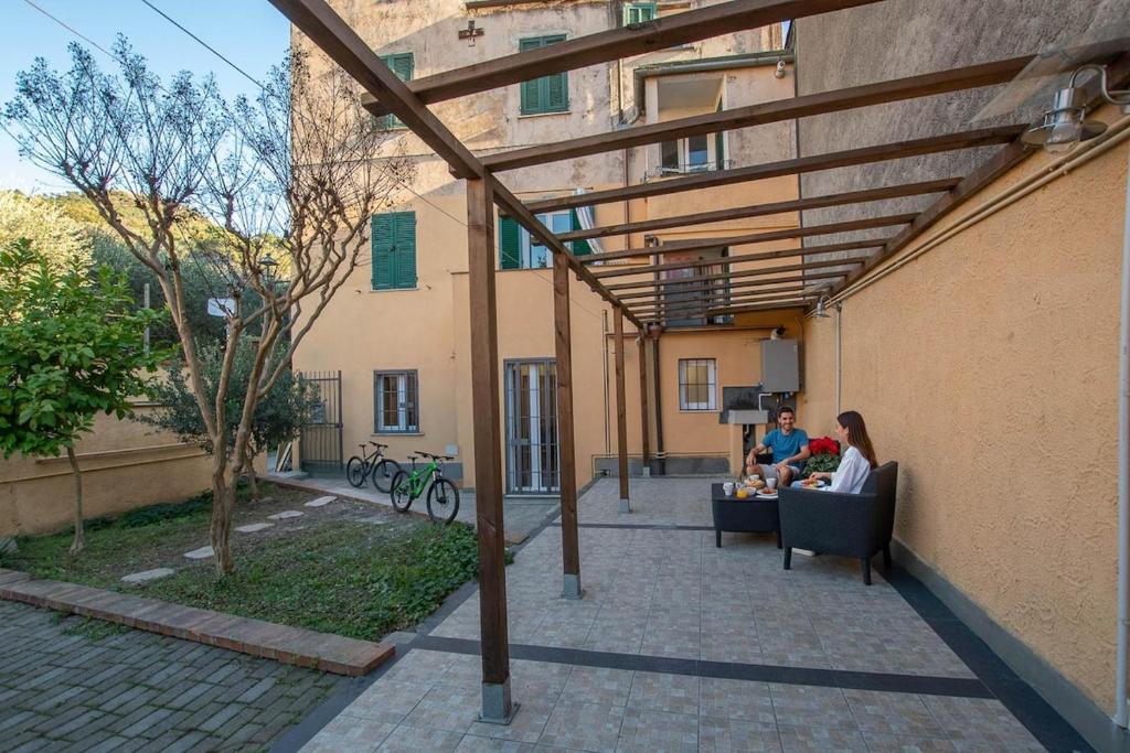 Eine Gruppe von Menschen sitzt auf Stühlen unter einer Markise vor einem Gebäude. in der Unterkunft Dalia's Home Garden and Private Parking in Calice Ligure