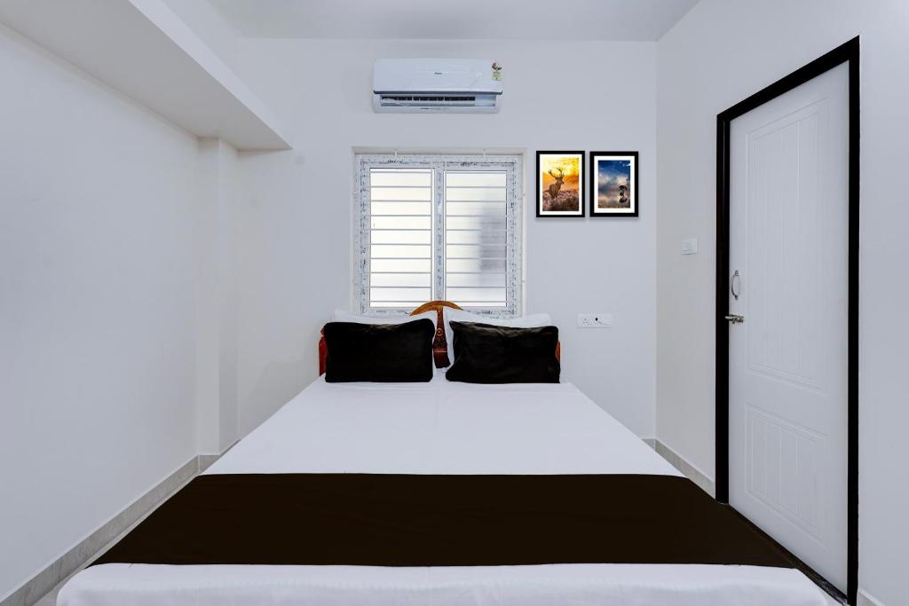 una camera da letto con un letto bianco con cuscini neri di Hotel O Eswar Guest House Padur a Chennai