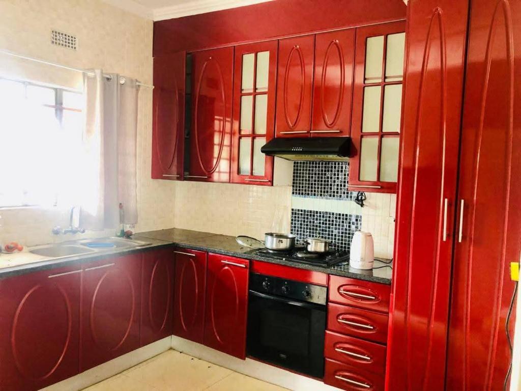 a kitchen with red cabinets and a black stove at Secret-Meadow Accommodation in Maun