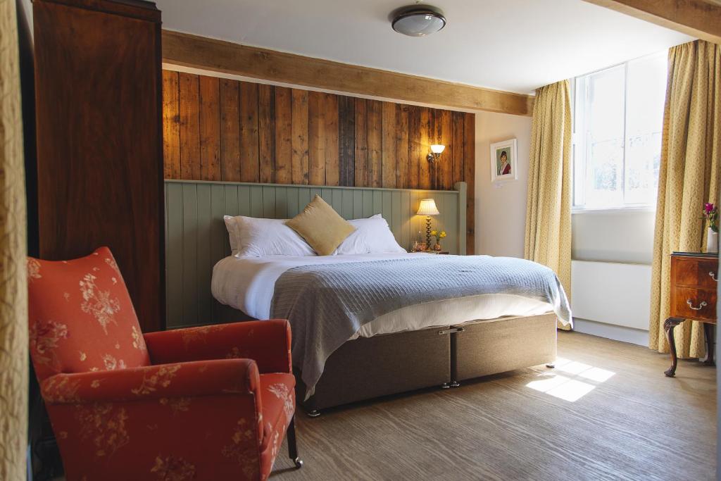 a bedroom with a large bed and a chair at Blue Ball Inn in Sidmouth