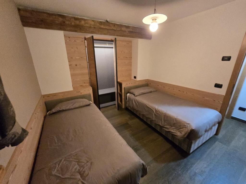 a small room with two beds and a lamp at Appartamento Rita in Pozza di Fassa
