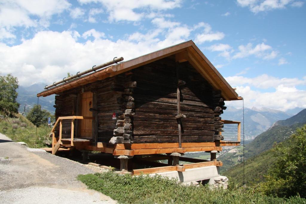 eine kleine Holzhütte auf einem Hügel mit Bergen im Hintergrund in der Unterkunft Studio Raccard Cendré in Grône