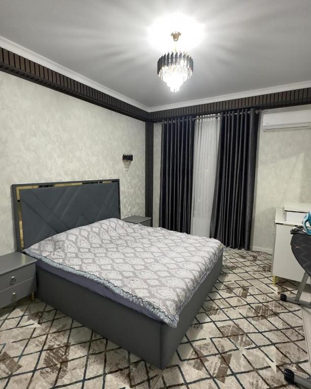 a bedroom with a large bed and a chandelier at КАРАВАН САРАЙ 15 Венеция in Türkistan