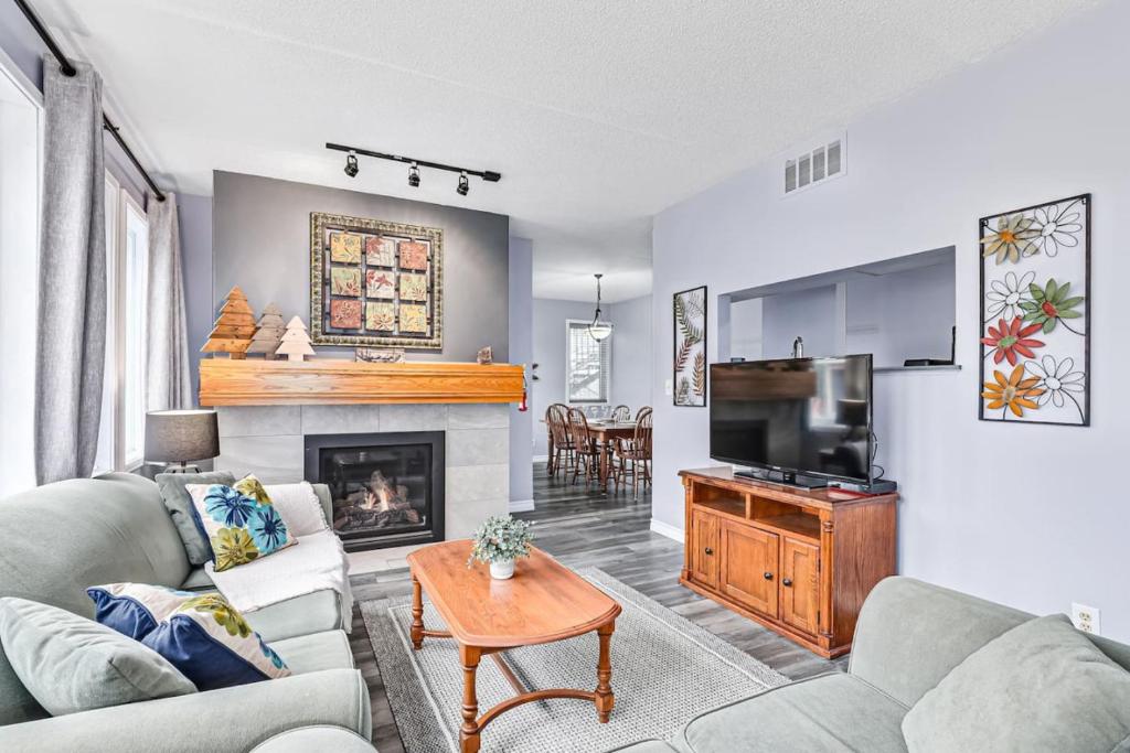 a living room with a couch and a television at 2BDR Condo Steps to Blue Mountain Village - 101 Cachet Crossing in Blue Mountains