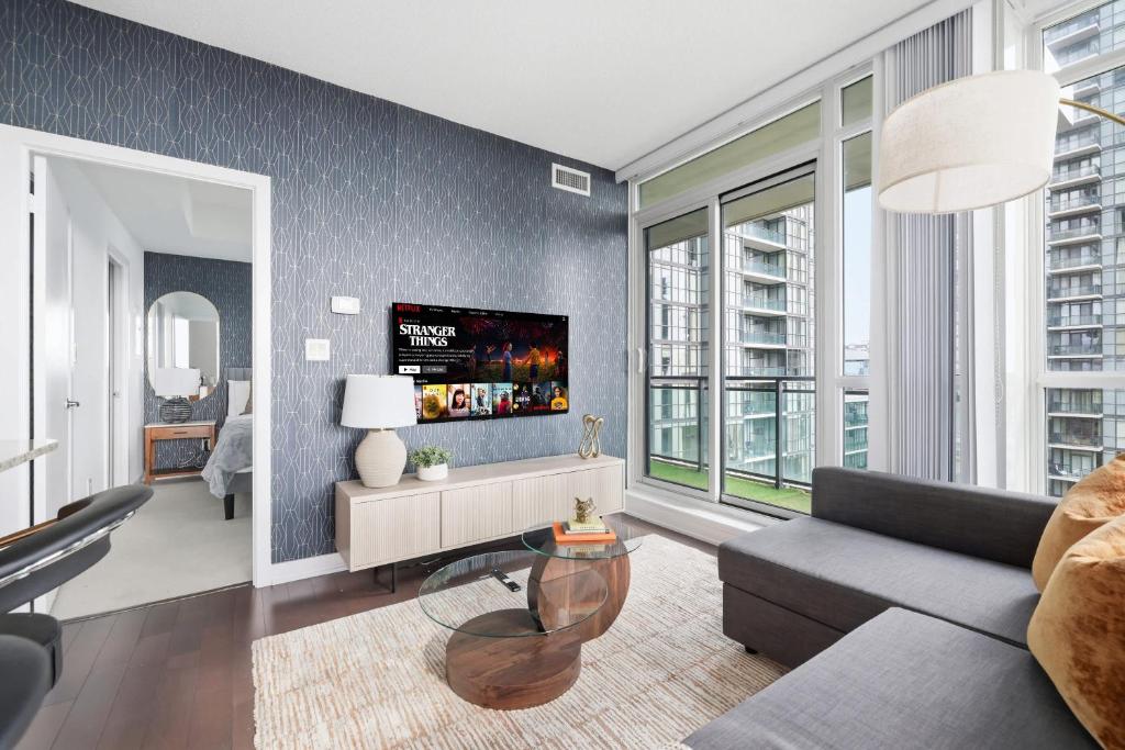 Stylish Downtown - Condo Sleeps 8 - YYZ Airport في ميسيساوغا: غرفة معيشة مع أريكة وتلفزيون