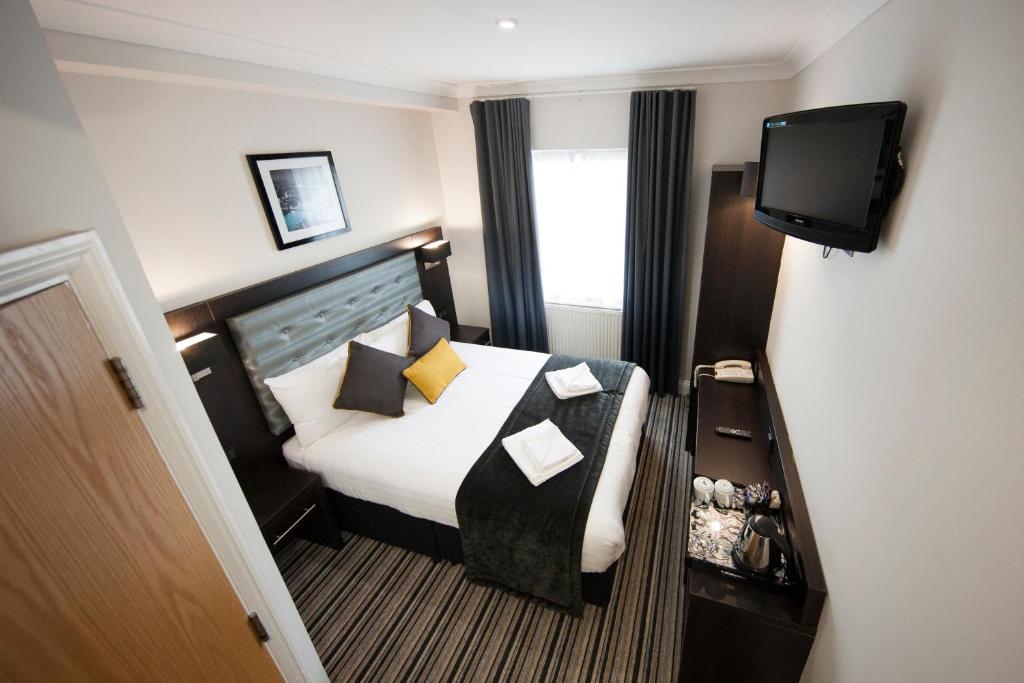 a hotel room with a bed and a television at St George's Inn Victoria in London