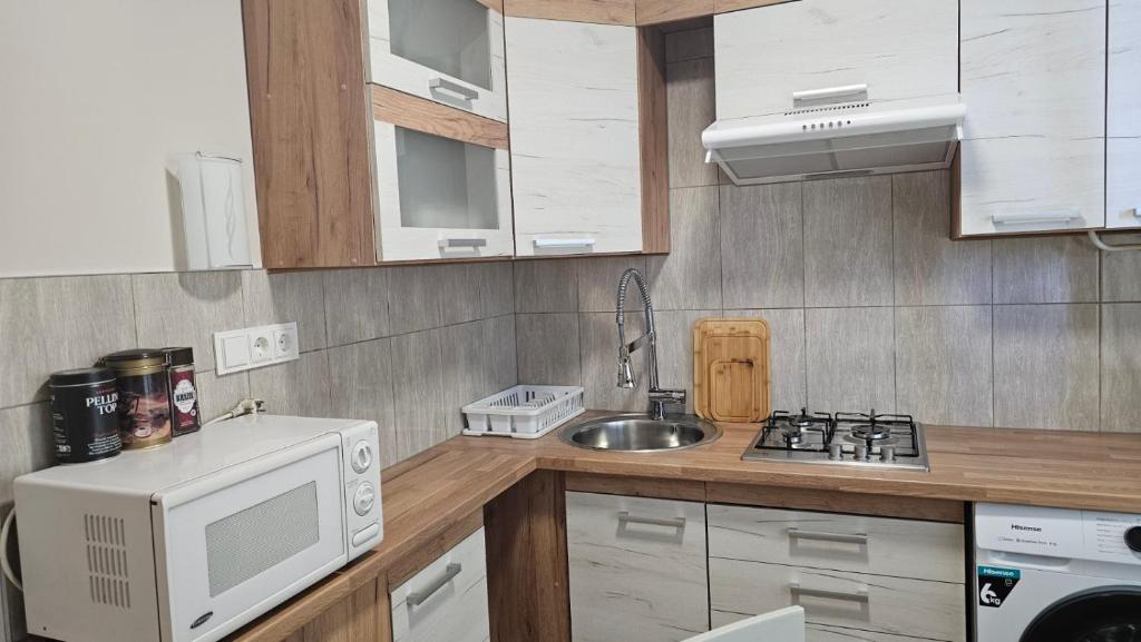 a small kitchen with a microwave and a sink at Kambarių nuoma Kaune Taikos pr in Kaunas