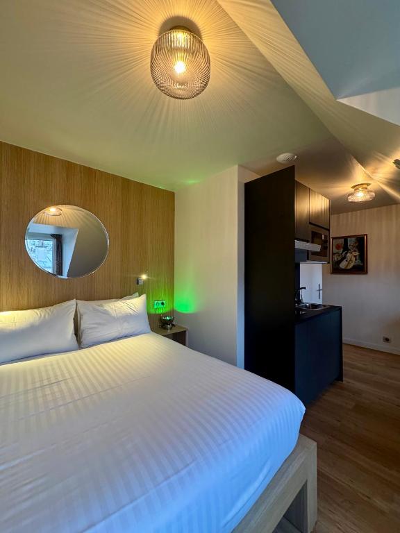 a bedroom with a large white bed and a mirror at Hôtel Montmartre - Nouvellement Rénové in Paris