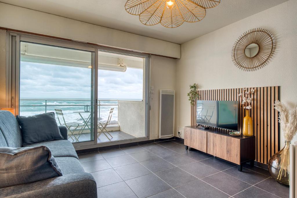 een woonkamer met een bank en uitzicht op de oceaan bij Premium Ocean View Studio, Balcony & Pool in Les Sables-dʼOlonne