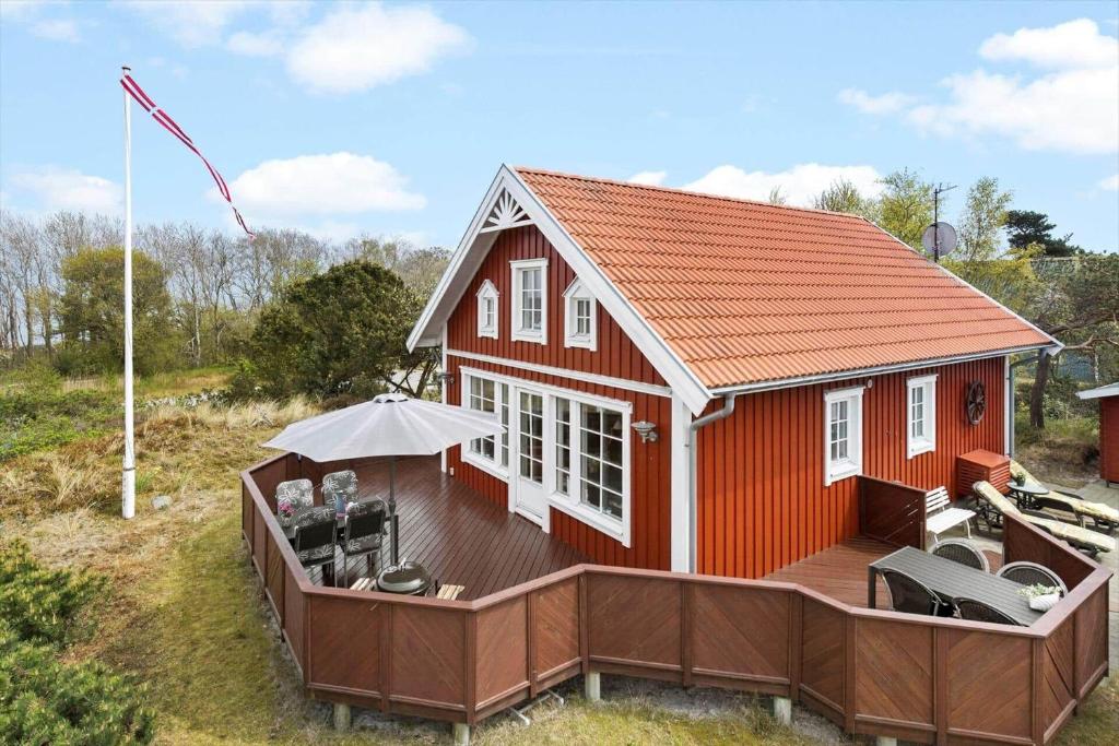 ein kleines rotes Haus mit einer Terrasse und einem Sonnenschirm in der Unterkunft 3690 Nexø - Hovedgade 2 in Snogebæk