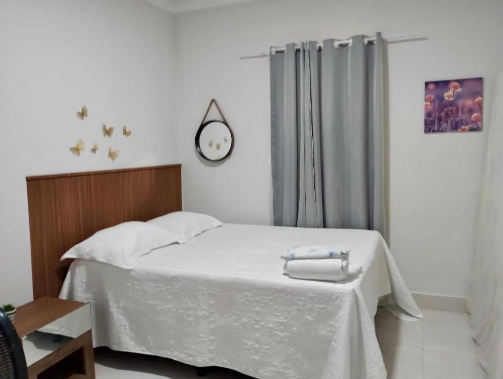 ein Schlafzimmer mit einem weißen Bett mit einer Uhr an der Wand in der Unterkunft Casa Vieira in Piranhas