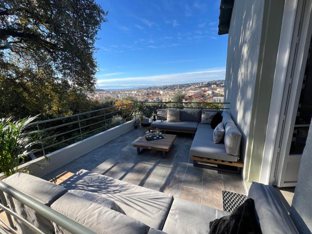 a patio with a couch and a table on a balcony at Golden hours luxury and panoramic view in Nice