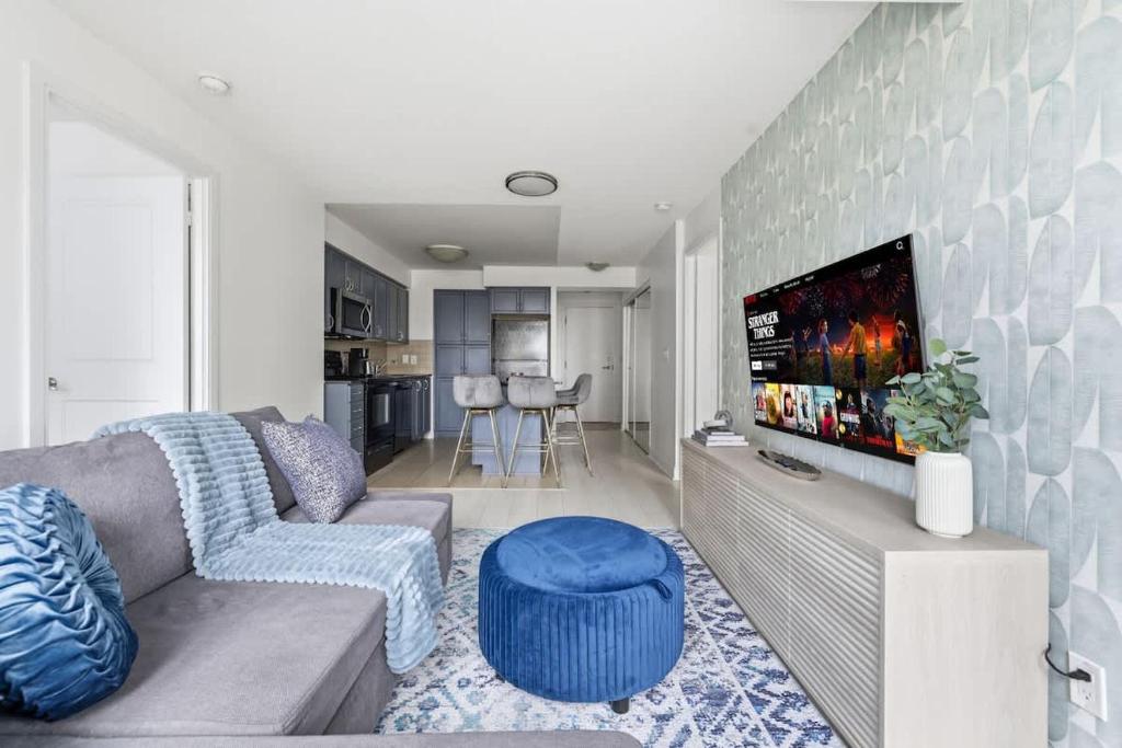 Designer 2BR - King Suite - Rare 2 Parking - YYZ في ميسيساوغا: غرفة معيشة مع أريكة وتلفزيون بشاشة مسطحة