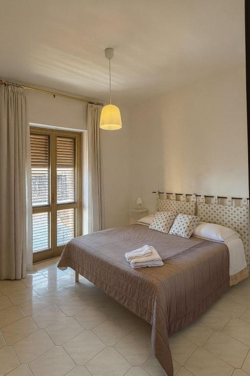 una camera con un grande letto e una lampada di Domus Poppea - a 5 minuti da Pompei e parcheggio gratuito a Torre Annunziata