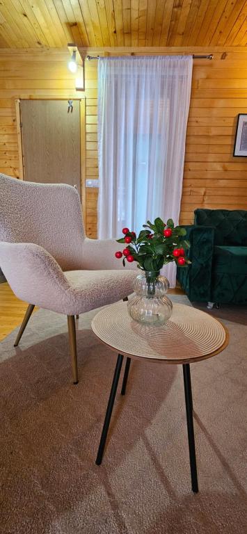 a room with two chairs and a table with a vase of flowers at Nadiaa Wood House in Ilidza