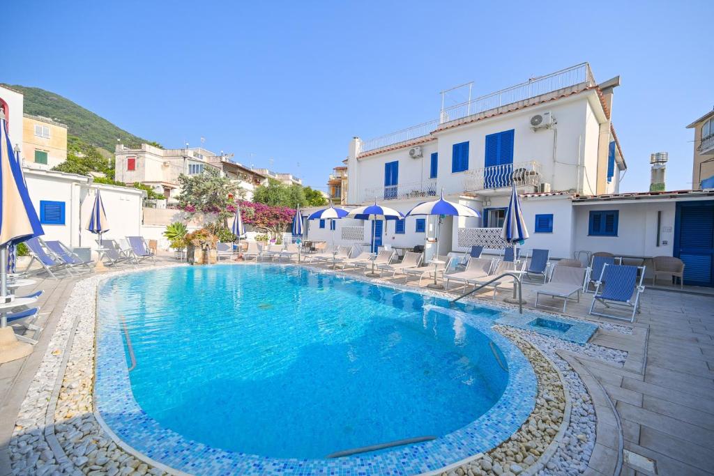 a large swimming pool with chairs and umbrellas at Charme Hotel La Villa Tina in Ischia