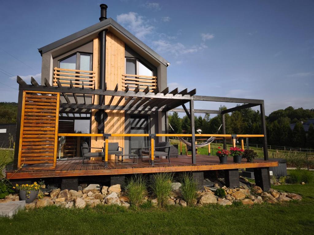 a house with a deck with a table and chairs at Dom z widokiem na góry in Zawodzie