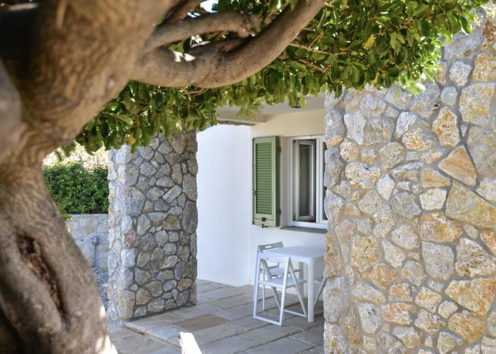 a stone building with a table and a tree at Bilocale Pianosa - riservato e fresco a soli 10 m dal mare in Pomonte