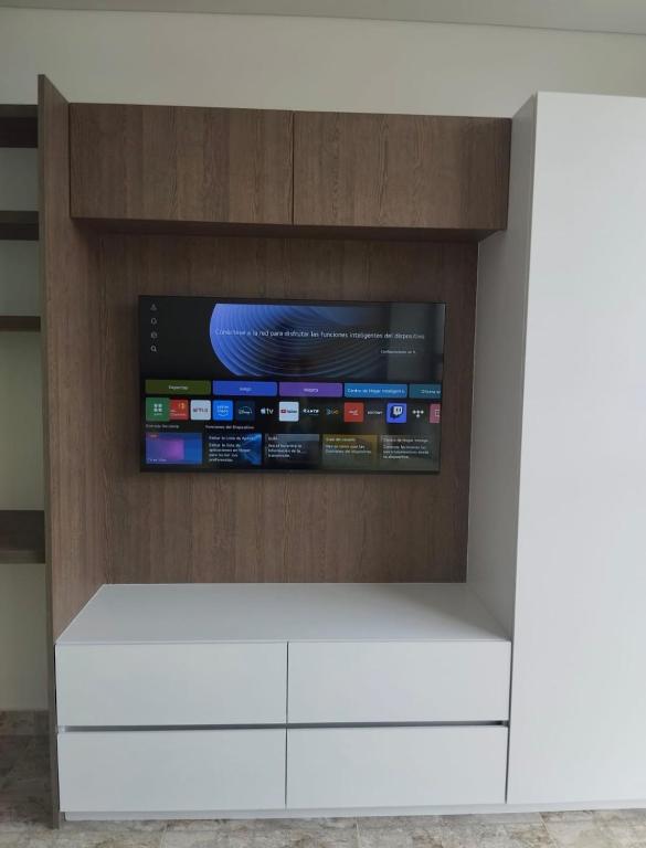 TV en la parte superior de un centro de entretenimiento blanco en Brand New Modern Apartment-Suite Meters from the Beach, en Gaira