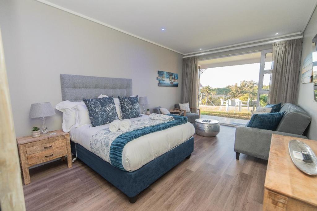 Un dormitorio con una cama grande y una sala de estar. en Brookes at Sea, en Gqeberha