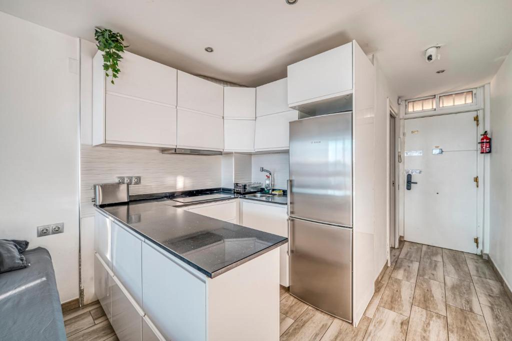 Una cocina con gabinetes blancos y un refrigerador de acero inoxidable. en Vistas al Mediterráneo - 4 Huéspedes, en Fuengirola