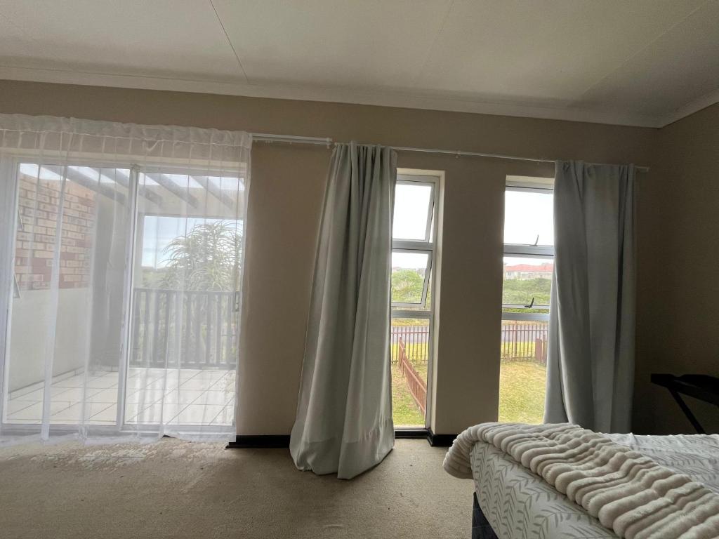a bedroom with a bed and a large window at The Grey Ivory in Port Alfred