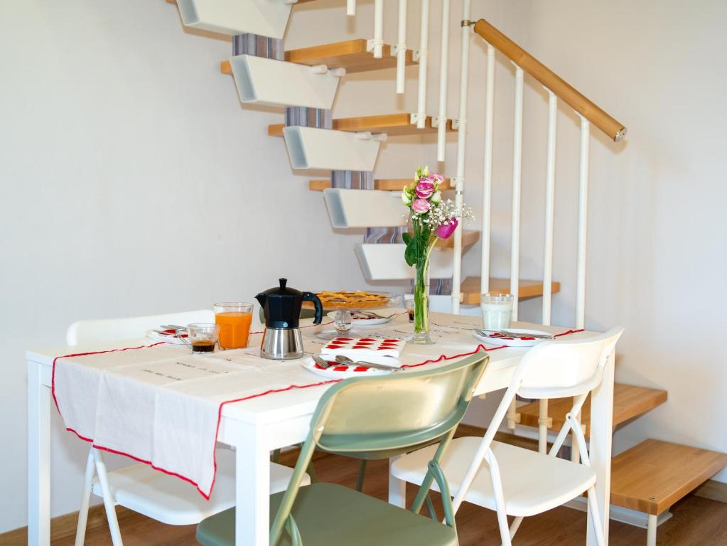 a dining room table with chairs and a staircase at CAERE RoGi House in Cerveteri