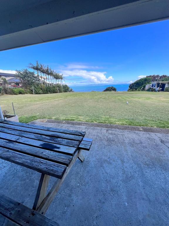 a bench sitting on a porch with a view of a field at Coopers Haven- Beachfront House in Coopers Beach