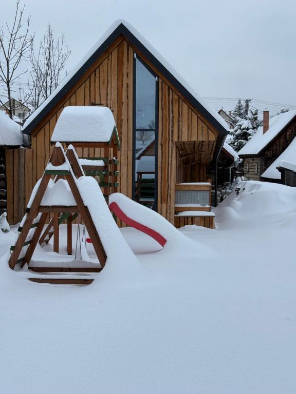 una baita ricoperta di neve con uno scivolo di Chata Pod Úbočou a Liptovská Teplička