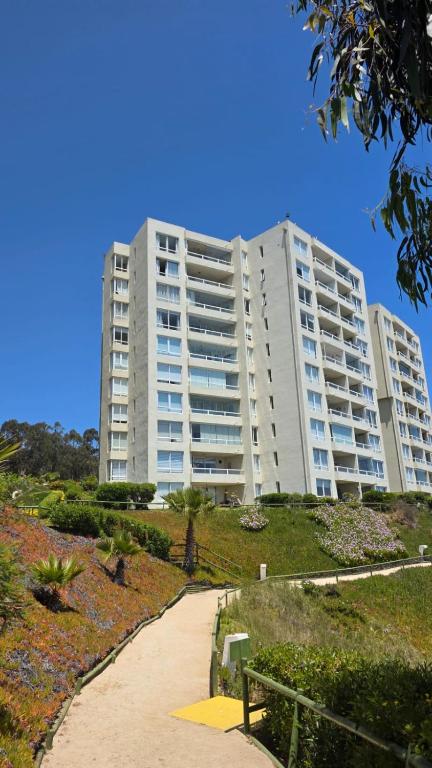 a large white apartment building with a path in front of it at CostaQuilen Departamento in Puchuncaví
