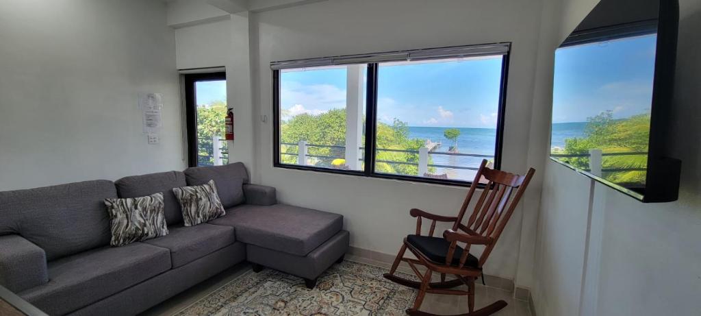 a living room with a couch and a chair and windows at Lickety Split 2 - Northside, Oceanview Retreat in Caye Caulker