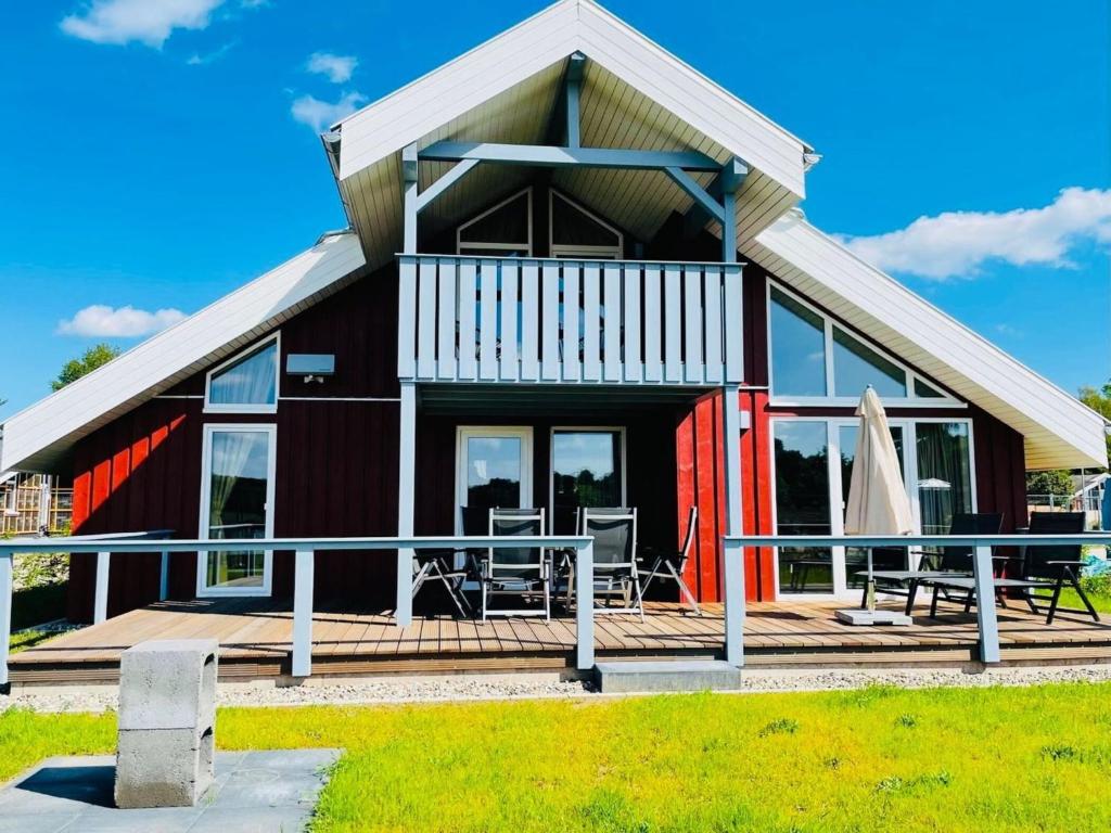 een rood huis met een balkon en een terras bij Ferienhaus im Ferienpark Mirow in Granzow