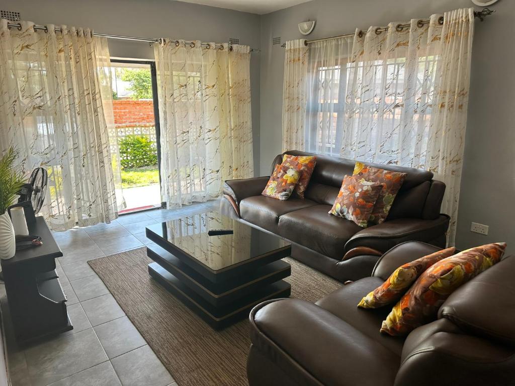 a living room with a leather couch and a glass table at Hatfield Staylax Manor 4 in Harare