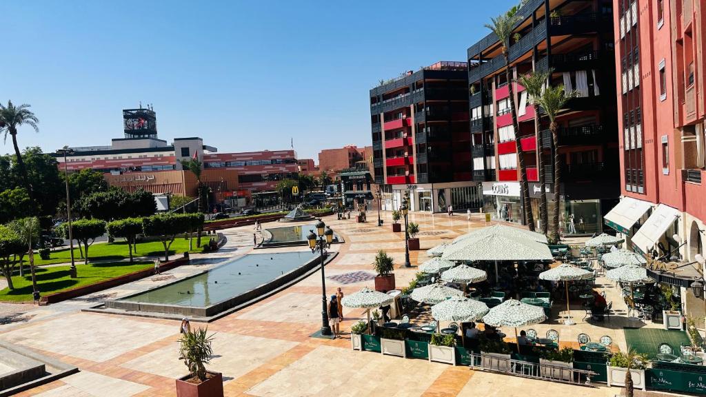 a city street with a pool and tables and umbrellas at Heart of Marrakech Chic & Central Gueliz Apartment - Free parking in Marrakech