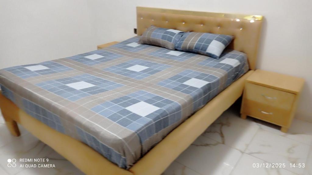 ein Schlafzimmer mit einem Bett mit einer blau-weißen Tagesdecke in der Unterkunft Beuleup Résidence in Rufisque