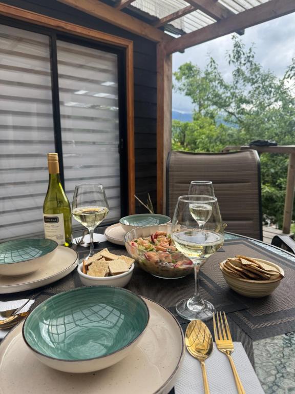 una mesa con platos de comida y copas de vino en Cabaña con vista al volcán, en Neltume