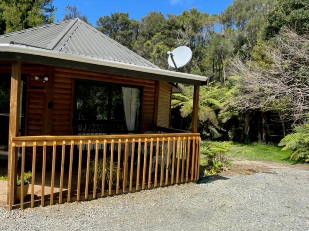 een blokhut met een veranda en een satelliet-tv bij Fern Cottage in Mangonui