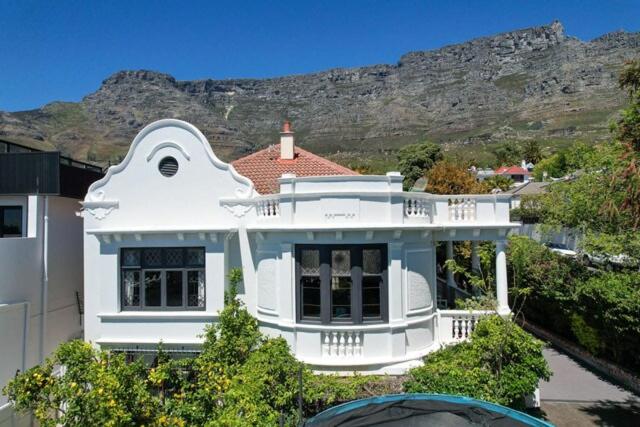 a white house with a mountain in the background at Authentic Cape Dutch Gem - Relax & Unwind in Cape Town