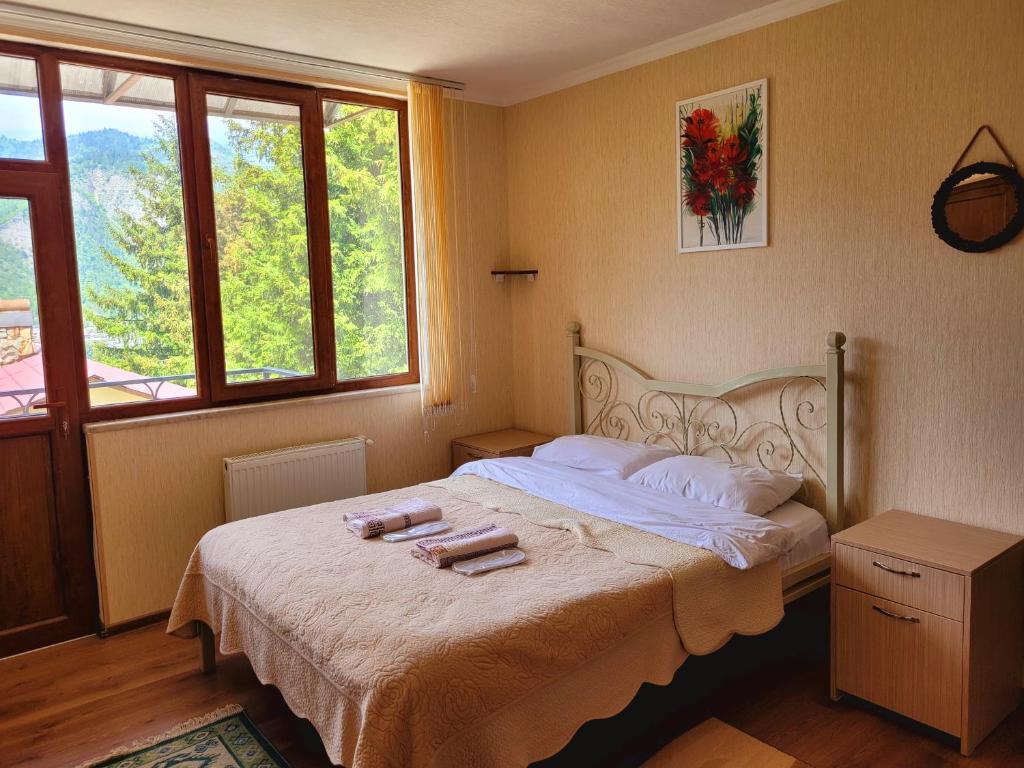 Hidden Forest Cottage في بورجومي: غرفة نوم مع سرير مع وجود شمعتين عليه