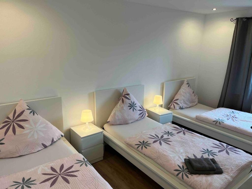 Nordschleife Apartments A2 في Quiddelbach: سريرين في غرفة بها مصباحين