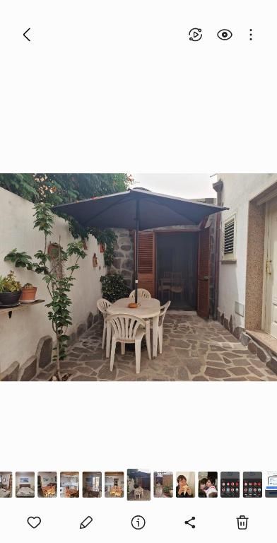 a patio with a white table and a blue umbrella at Casa Tommy in Olbia