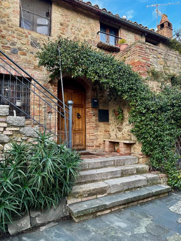 a brick house with stairs leading to a wooden door at Appartamento Kira in Porrona