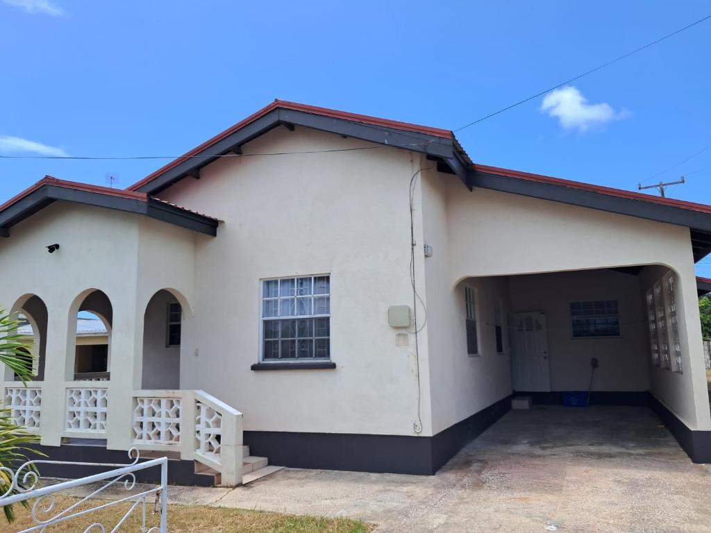 Lovely 3-bedroom house located near Oistins, close to beaches and Golf course في كرايست تشيرش: منزل أبيض مع مرآب للسيارات