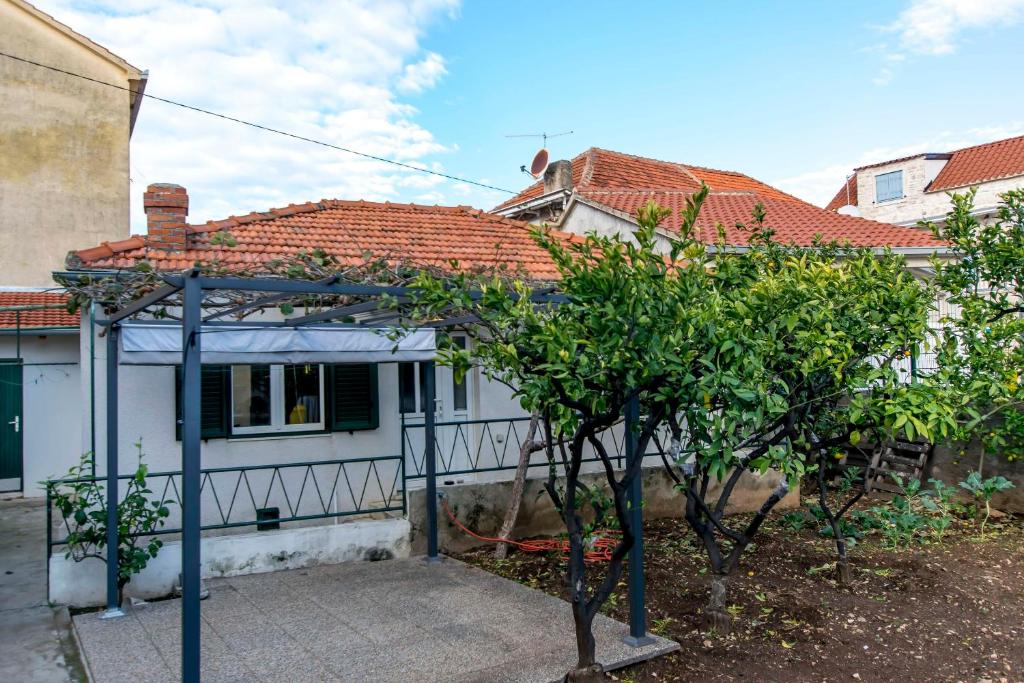 una piccola casa bianca con un albero di fronte di House Frane a Supetar (San Pietro di Brazza)