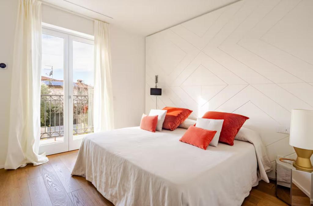 a white bedroom with a large bed with red pillows at Villa JD in Forte dei Marmi
